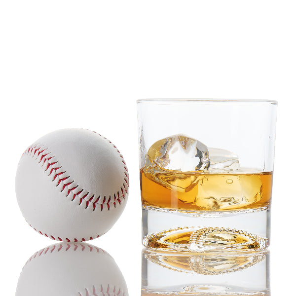 High-quality baseball ball whiskey glass resting on a wooden bar top, highlighting the etched baseball bottom and smooth rim designed for comfortable sipping.