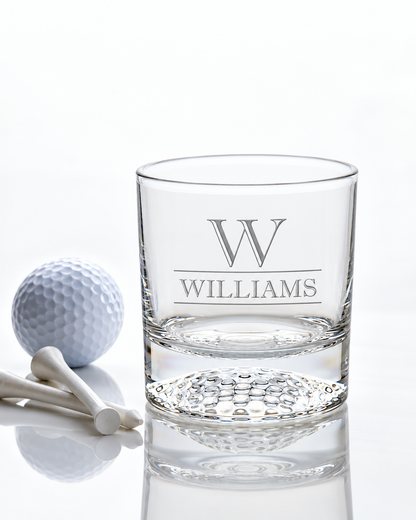 Clear glass with engraved design and liquid on a black cube against a dark background Personalized Golf Ball Whiskey Glass Set Rock Bourbon Glass Groomsmen Gift Golf Father Day Gift Golf Gifts for Men Custom Scotch Glass Chill