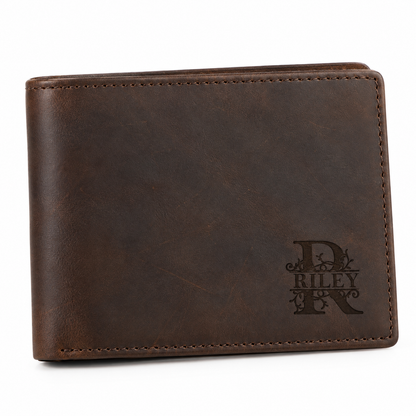 Personalized brown leather bifold wallet for men with RILEY monogram engraving on the lower right corner, photographed on a clean white background. The lighthouse goods