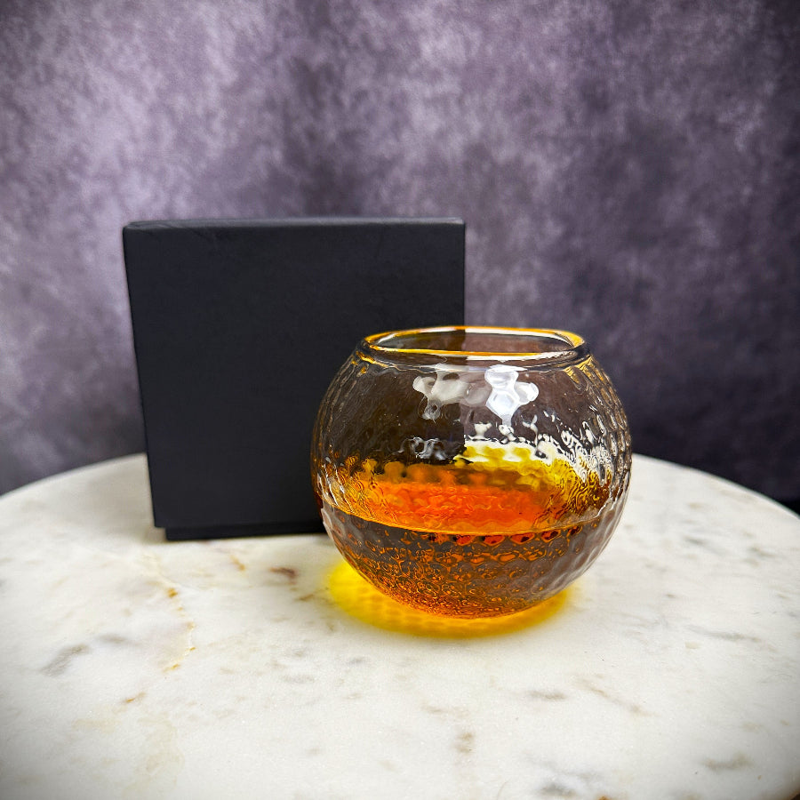 Whiskey glass shaped like a golf ball, ideal for gifting to golf fans, husbands, and partners who enjoy fine spirits