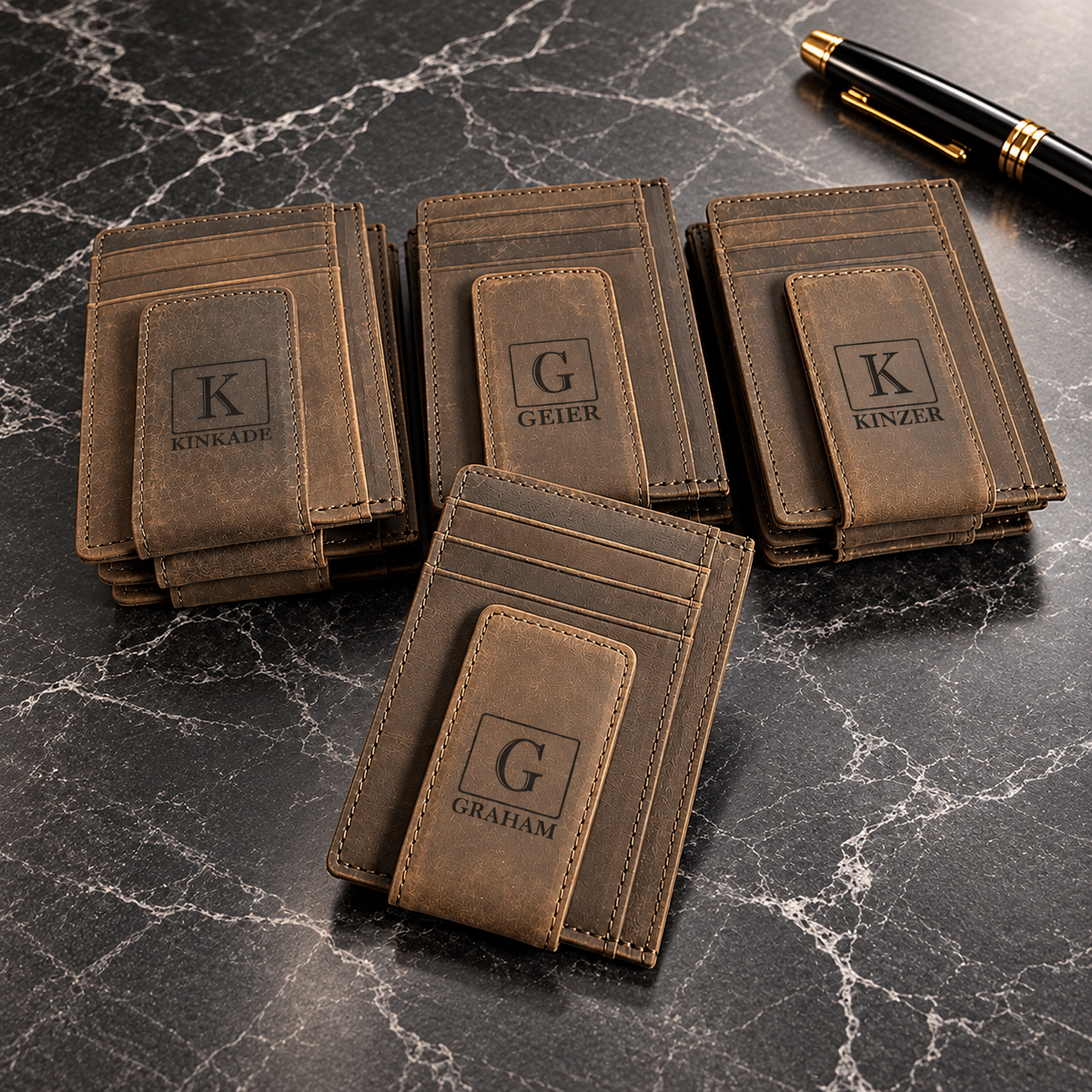 Four personalized brown leather slim wallets with custom engraved initials and names, featuring card slots and money clips, displayed on a luxury black marble tabletop